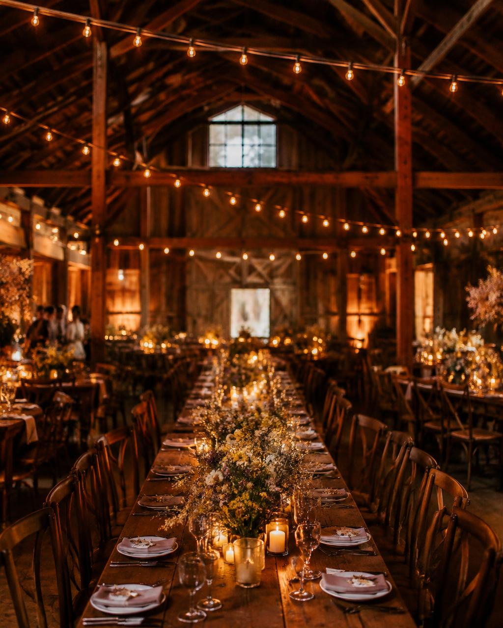 Festoon lights and long farm tables inside the barn