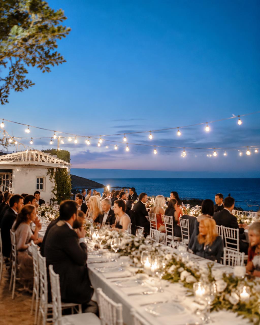 Long tables under string lights at blue hour