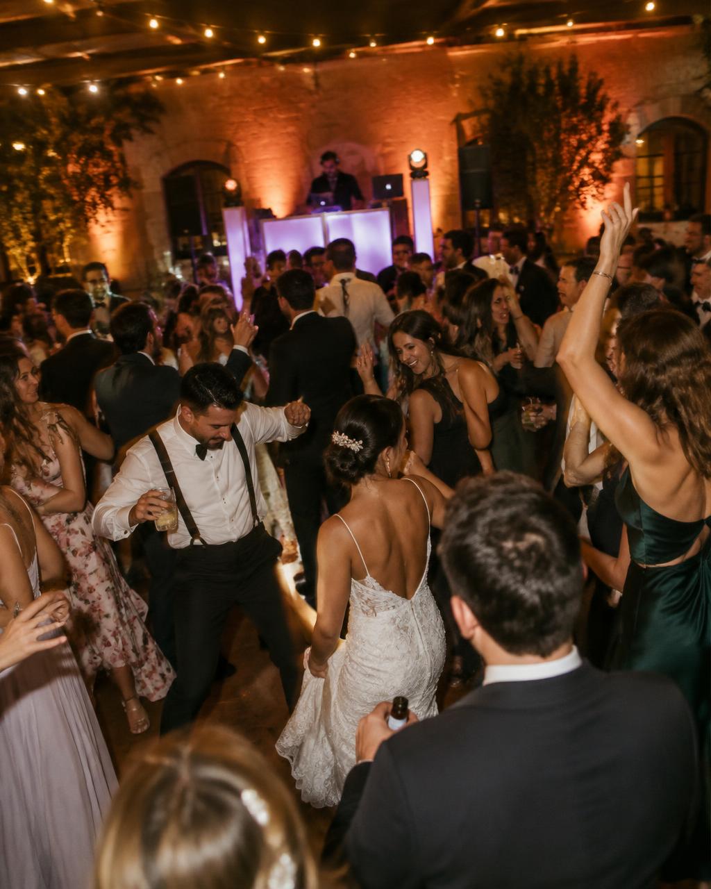 A full dance floor with warm uplighting and string lights